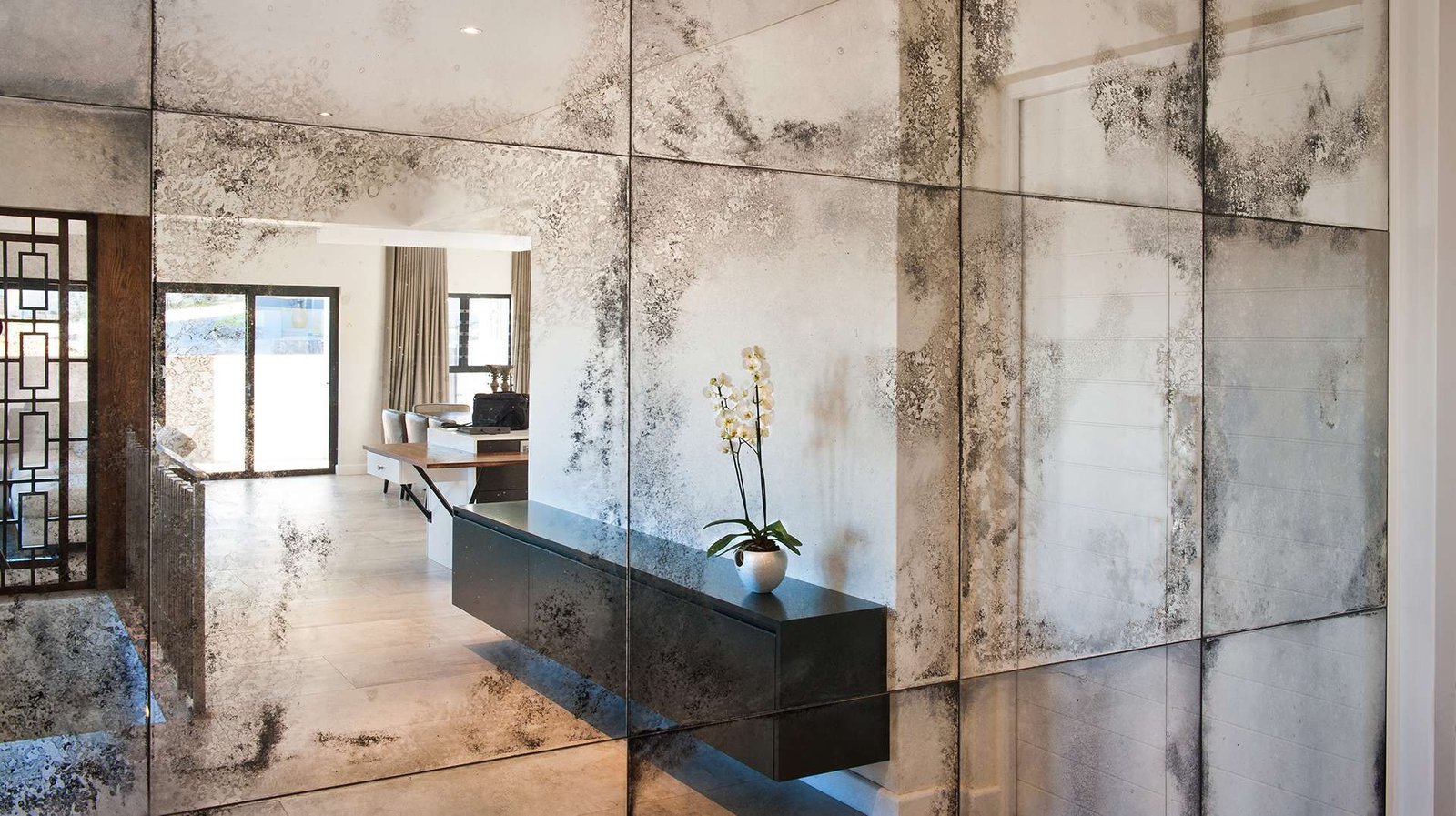 Antique mirror wall panels with a distressed finish, designed by D&E Decor, reflecting a modern and elegant interior space.